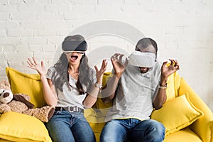 scared african american couple in virtual reality headsets sitting