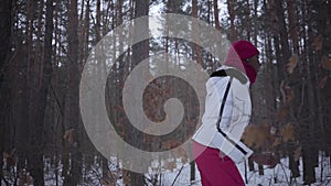 Scared African american young woman dressed warm wearing a red hat, scarf and white jacket running through the snowy