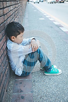 Scared and alone, young Asian child who is at high risk of being bullied, trafficked and abused, selective focus