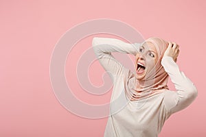 Scared arabian muslim woman in hijab light clothes posing isolated on pink background studio portrait. People religious