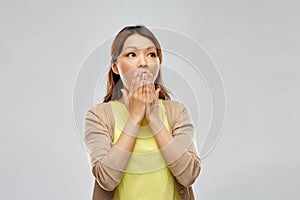 Scared asian woman over grey background