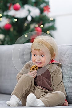 Scared baby in Christmas deer suit with cookie