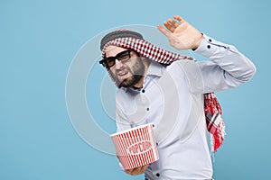 Scared bearded young arabian muslim man in keffiyeh kafiya ring igal agal 3d imax glasses isolated on pastel blue photo