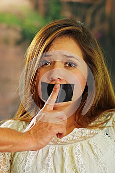 Scared beautiful young woman being silenced with tape on her mouth