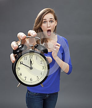 Scared beautiful young woman standing with a clock for stressful deadlines