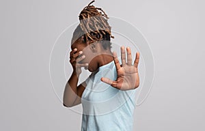 Scared black woman covering face with hand, showing no gesture