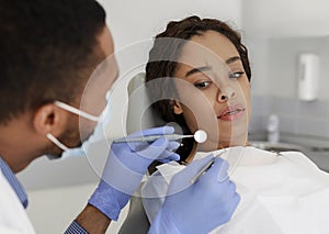 Scared black woman looking at dental tools in doctor hands