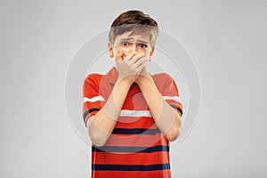 Scared boy clothing mouth with hands