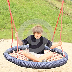 Scared boy sitting on a net swing