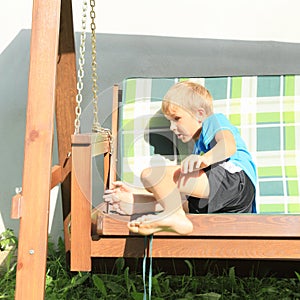 Scared boy sitting on a wooden swing