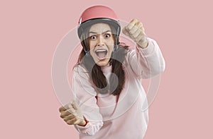 Scared brunette woman imagines she is driving car and holding steering wheel on pink background.