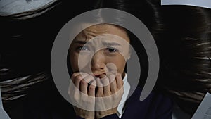 Scared business woman looking at documents and nervously biting nails, deadline