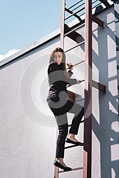 scared businesswoman looking down while climbing stairs on rooftop.