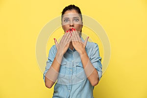 Scared casual woman gasping, covering her mouth with both hands