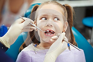 Scared child sits at dentist chair with open mouth