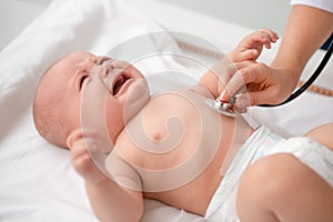 Cute baby lying on the couch during the chest auscultation