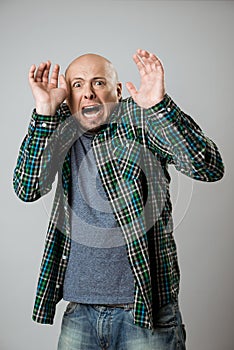 Scared emotive young man shouting over beige background.