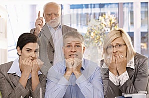 Scared employees sitting with angry boss behind