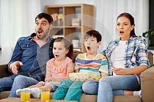 Scared family with popcorn watching horror on tv