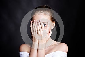 Scared girl covering her face with her hands