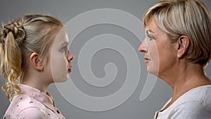 Scared girl looking at strict grandmother, difficult childhood, generation gap