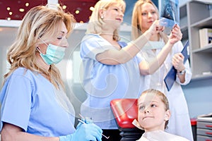 Scared girl patient with dentist, assistant and nurse in a dental office.