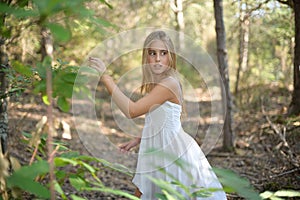 Scared girl running through a forest and looking back