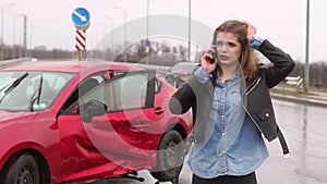 Scared girl talking on the phone after a car accident in the rain, car is broken