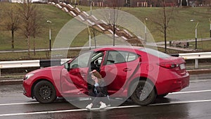 Scared girl talking on the phone after a car accident in the rain, car is broken