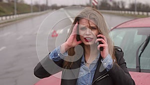 Scared girl talking on the phone after a car accident in the rain, car is broken