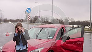 Scared girl talking on the phone after a car accident in the rain, car is broken