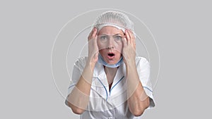 Scared horrified woman doctor on grey background.