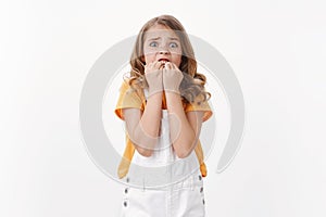 Scared innosent timid little girl with blond hair and blue eyes, panic, standing alone white background, biting fingers