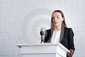 scared lecturer suffering from fear of public speaking while standing on podium tribune.