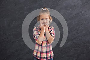 Scared little girl covering mouth with hands