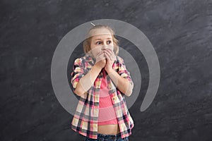 Scared little girl covering mouth with hands
