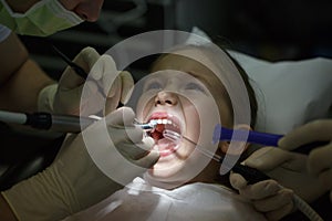 Scared little girl at the dentists office, in pain during a treatment