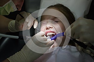 Scared little girl at the dentists office, in pain during a treatment