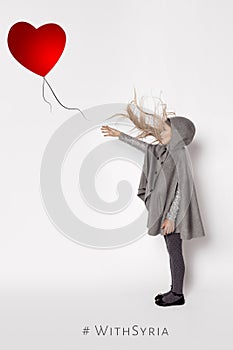 Scared little girl stands on a white background and holds out his hand after the balloon