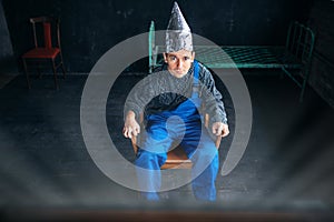 Scared man in aluminum foil hat sits in chair