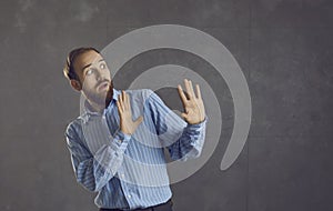 Scared man doing stop gesture afraid of terrible danger isolated on grey background