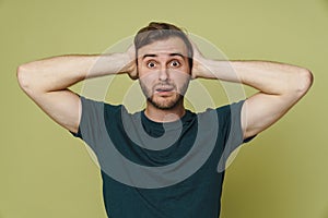 Scared man grabbing his head in panic isolated over green background