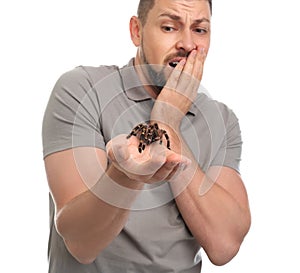 Scared man holding tarantula on background. Arachnophobia fear of spiders