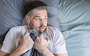 Scared Man Lying In Bed At Home At Night