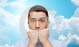 Scared man over blue sky and clouds background