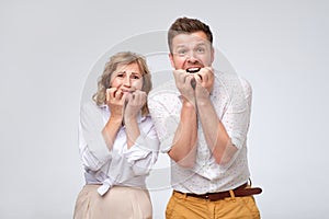 Scared man and woman biting their nails feeling stressed and surprised.