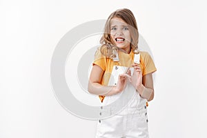 Scared reluctant blond little girl with blue eyes express disgust and aversion, cringe from awful smell, raise hands photo