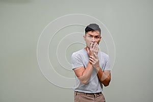 Scared and shocked millennial Asian man covering his mouth. isolated background photo