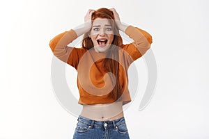 Scared and shocked young redhead woman witness terrible scary accident, grab head in panic and frustration, screaming