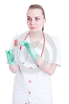 Scared woman doctor looking panicked to a syringe with needle
